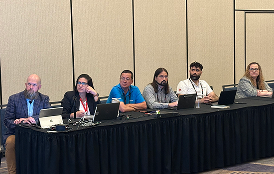 A group of AEM Sustainability Council members listen to a presentation around a table