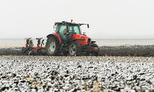 A tractor plowing a field in the snow.